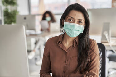 Female professional with protective face mask at work place - ABIF01298