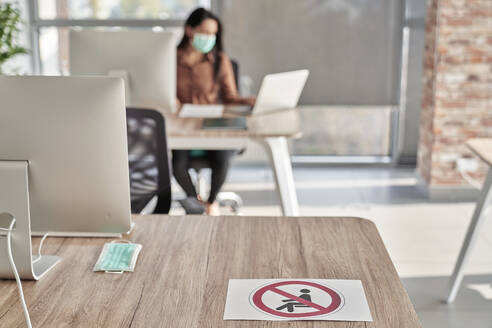 Female professional working on laptop in office during COVID-19 - ABIF01305