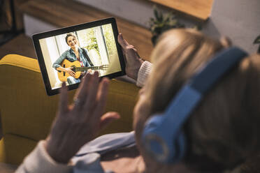 Mother waving to daughter on video call through digital tablet in living room - UUF22667