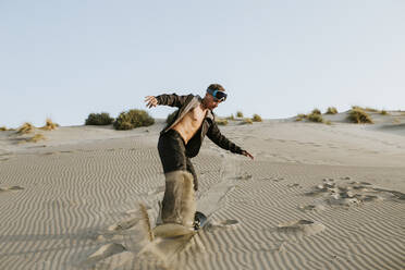 Junger Mann beim Snowboarden auf Sand in Almeria, Tabernas-Wüste, Spanien - MIMFF00432