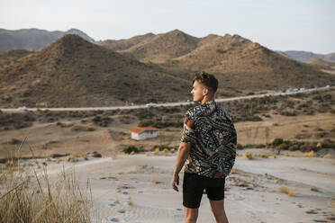 Junger Mann steht in der Wüste von Almeria, Tabernas, Spanien - MIMFF00444