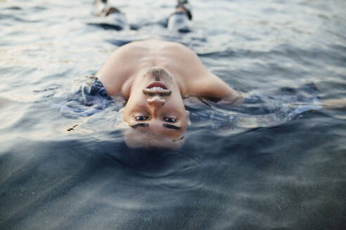 Junger Mann schwimmt im Wasser - MIMFF00458