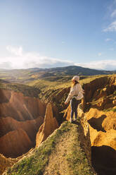 Carefree young woman standing on rock formation against sky at Valdepenas de la Sierra, Spain - RSGF00499