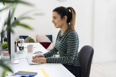 Kreative Geschäftsfrau arbeitet am Computer am Schreibtisch im Büro - GIOF10630