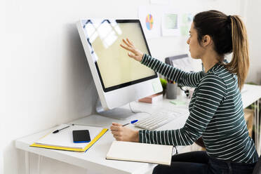 Kreative Geschäftsfrau berührt den Computerbildschirm bei der Arbeit im Büro - GIOF10642