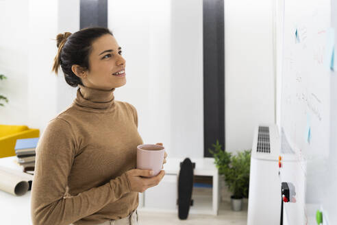 Frau mit Kaffeetasse schaut auf mathematische Formel an Bord - GIOF10665