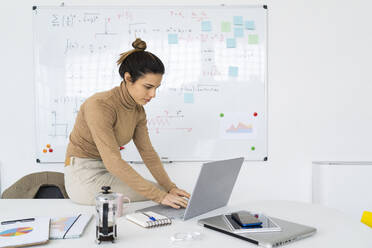 Young female student using laptop while doing math - GIOF10668