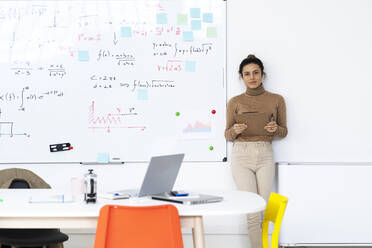 Female student with clipboard standing by whiteboard at home - GIOF10679