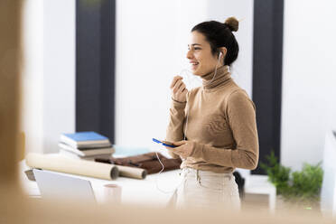 Young woman having phone call while talking through earphones - GIOF10685