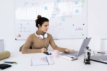 Young female student with headphones studying on laptop - GIOF10689