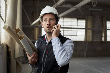 Male real estate developer talking over mobile phone while standing in building - VEGF03592