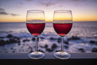 Zwei Gläser Rotwein mit Meer bei Sonnenuntergang im Hintergrund - SIEF10065