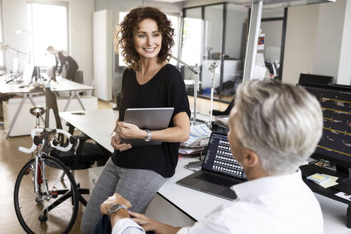 Smiling businesswoman having discussion with colleague at office - PESF02486