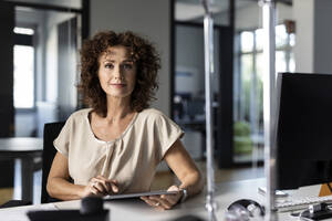 Confident businesswoman using digital tablet while sitting at office - PESF02504