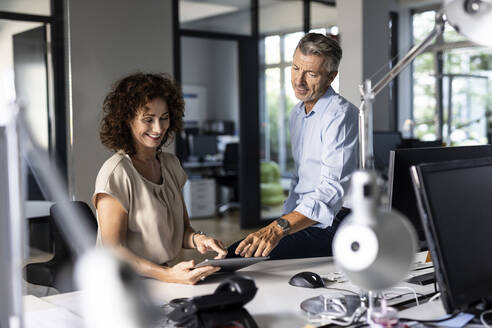 Business people discussing over digital tablet while sitting at office - PESF02511