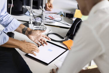 Unternehmer bei der Arbeit über ein digitales Tablet mit einem Kollegen im Büro - PESF02539