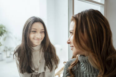 Smiling girl looking at mother through window at home - RCPF00629