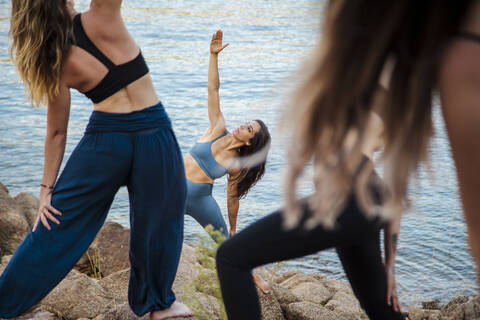 Young female yoga instructor teaching stretching exercise to women stock photo