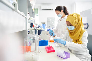 Wissenschaftlerinnen mit Gesichtsmasken und Hidschab bei der Arbeit im Labor - CAIF30099