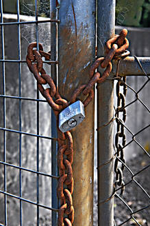 Rusty chain and padlock on a metal fence gate. - MINF15550