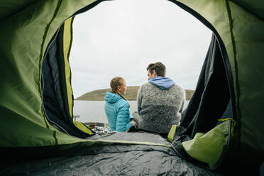 Couple resting near tent on seashore - CAVF91757