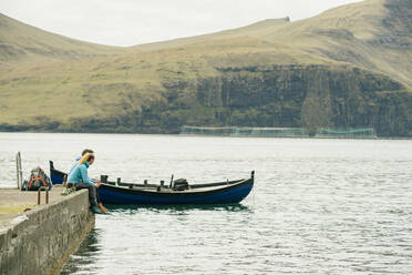 Anonymous tourists resting on quay near boat - CAVF91763