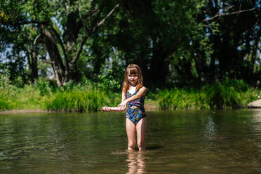 Junges glückliches Mädchen, das an einem sonnigen Sommertag in einem Fluss spielt - CAVF91782