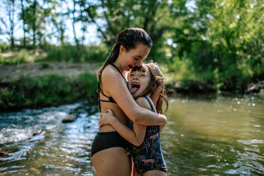 Zwei Mädchen umarmen sich und lachen an einem warmen Sommertag - CAVF91784