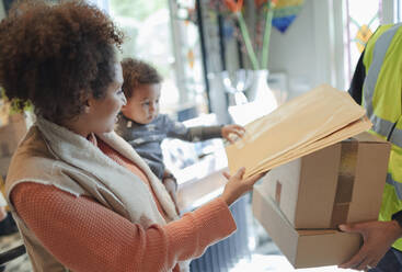 Mutter und kleine Tochter erhalten ein Paket von einem Zusteller - CAIF30145