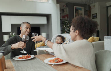 Glückliches Paar mit kleiner Tochter genießt Wein und Spaghetti-Essen - CAIF30154