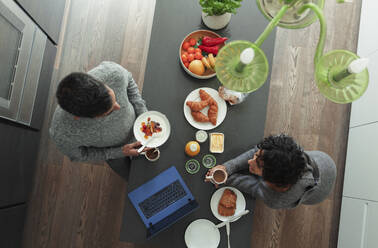 Ehepaar frühstückt am Küchentisch mit Laptop - CAIF30161
