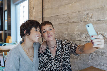 Freunde machen ein Selfie mit dem Handy, während sie im Restaurant sitzen - JRVF00105