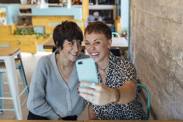 Junge Freunde lächelnd während der Aufnahme von Selfie durch Handy sitzen im Restaurant - JRVF00114