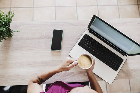 Geschäftsfrau mit Laptop und Kaffeetasse auf dem Tisch im Büro zu Hause - EBBF02211