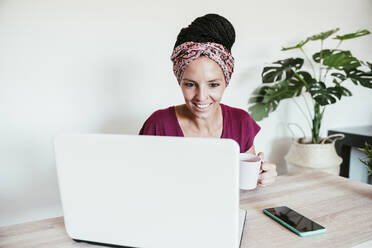 Freiberuflerin mit Kaffeetasse und Laptop zu Hause - EBBF02212