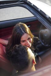 Smiling woman looking at man while sitting in car - OCMF01976