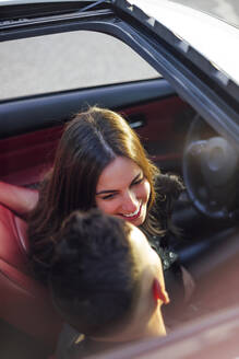 Lächelnde Frau schaut Mann an, während sie im Auto sitzt - OCMF01976