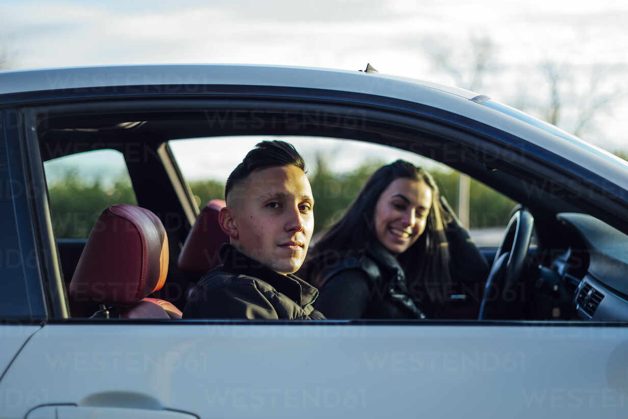 Junger Mann starrt beim Sitzen im Auto mit Frau bei Sonnenuntergang, lizenzfreies  Stockfoto