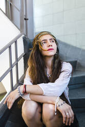 Hippie nachdenkliche junge Frau mit langen Haaren sitzt auf Stufen - JMPF00801