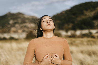 Beautiful woman with eyes closed standing in field during sunset - TCEF01428