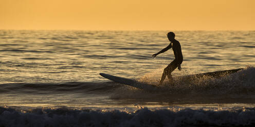 Silhouette Mann beim Surfen auf dem Meer gegen den klaren Himmel bei Sonnenuntergang, Pembrokeshire, Wales, UK - ALRF01789