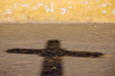 Schatten eines Kruzifixes auf einem Straßenpflaster. - MINF15585