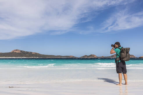 Mann mit Rucksack beim Fotografieren der türkisfarbenen Bucht, Westaustralien - FOF11949