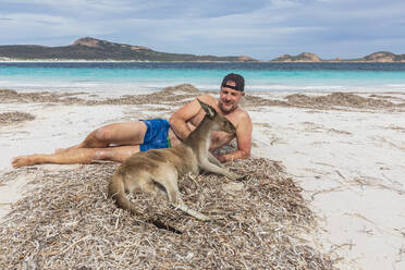 Mann mit Westlichem Grauen Känguru am Strand liegend, Westaustralien - FOF11955