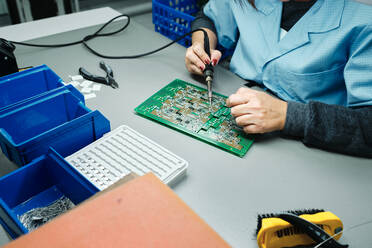 Person welded motherboard with a welder on a work table - CAVF91903