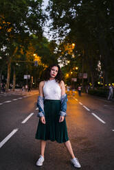 Beautiful woman wearing denim jacket posing on road in park at dusk - JMPF00838