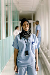 Portrait of smiling female nurse standing in hospital corridor - MASF21246