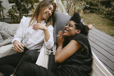 Cheerful female friends talking while enjoying during garden party - MASF21253