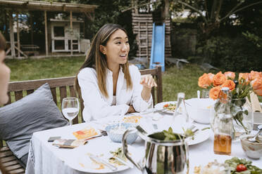 Smiling woman talking while sitting at table during social gathering - MASF21257