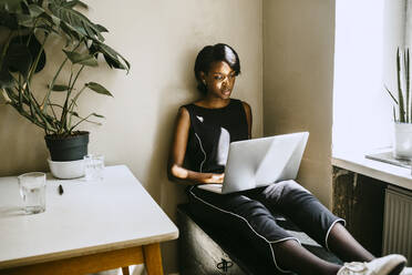 Female entrepreneur using laptop while sitting in office - MASF21284